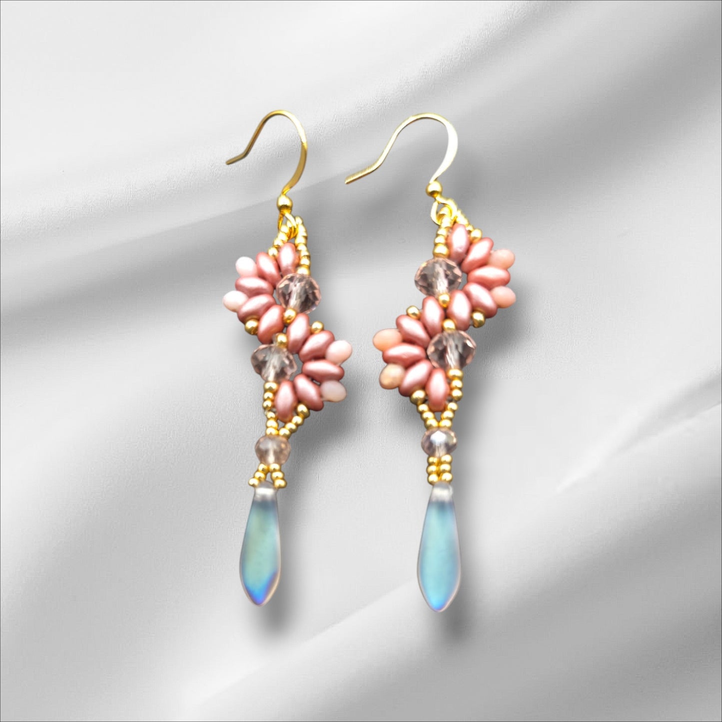 a pair of pink and blue earrings on a white background