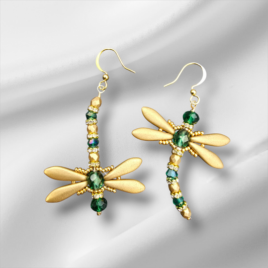 a pair of dragonfly earrings with green and gold beads