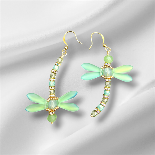 a pair of green dragonfly earrings on a white background