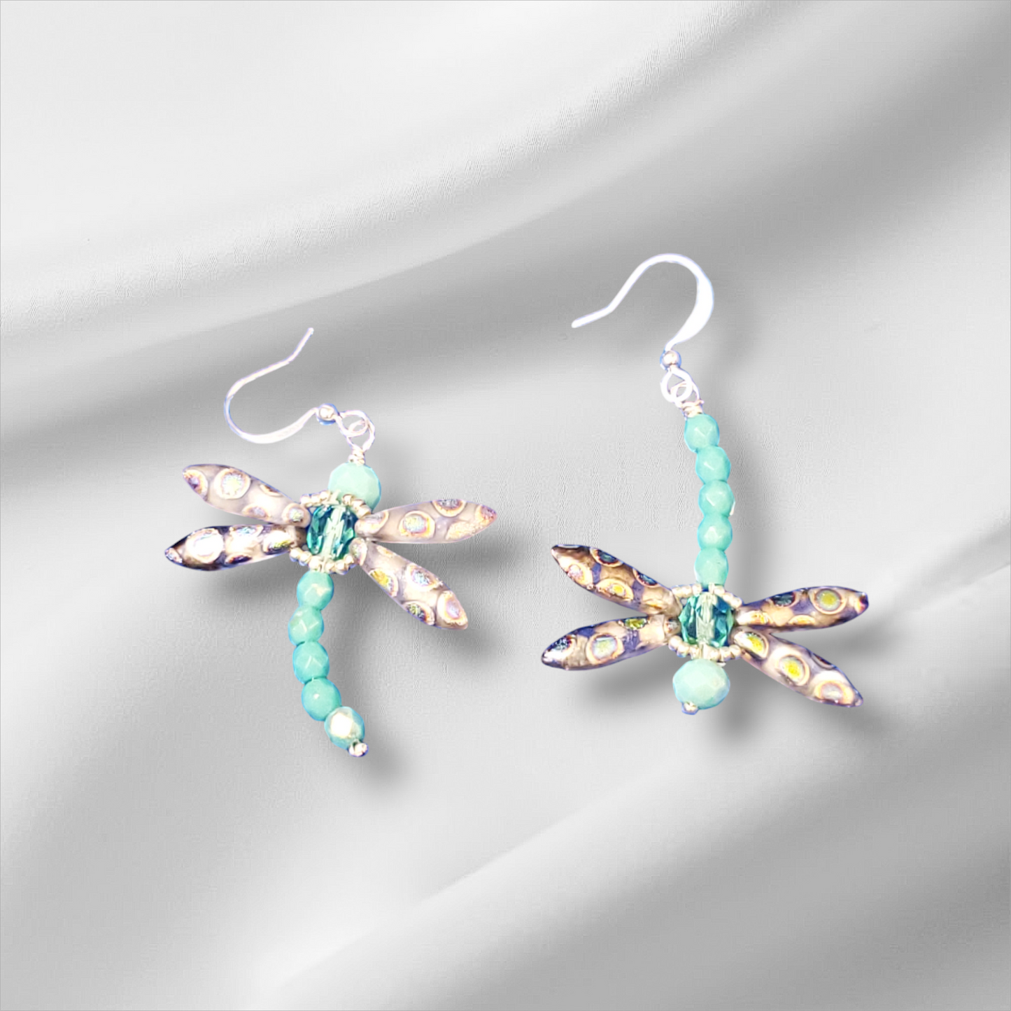 a pair of dragonfly earrings with turquoise beads