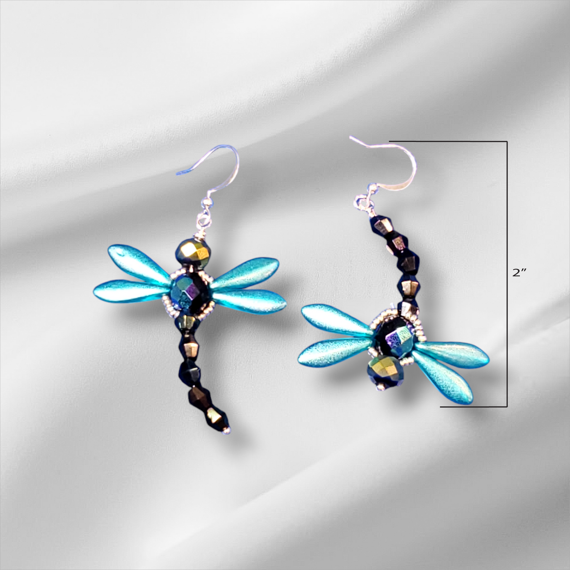 a pair of blue dragonfly earrings on a white background