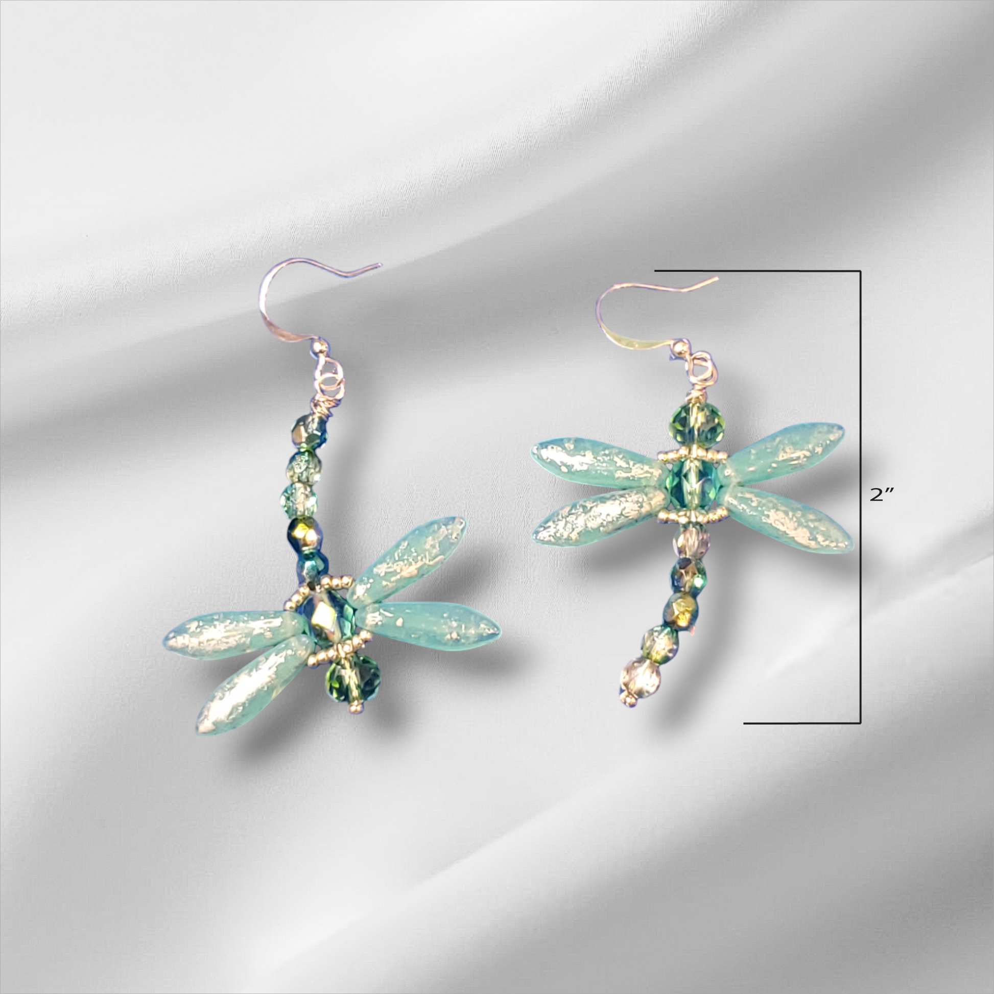 a pair of earrings with dragonflies on them