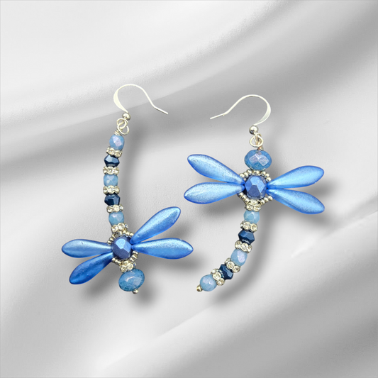 a pair of blue dragonfly earrings on a white background