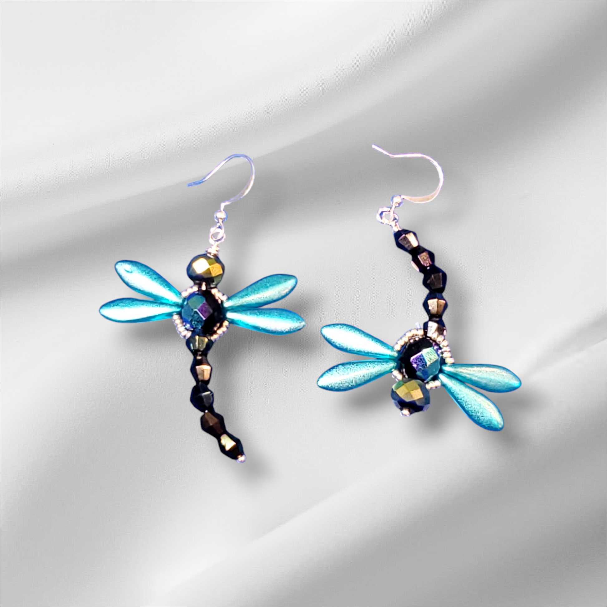 a pair of blue dragonfly earrings on a white background